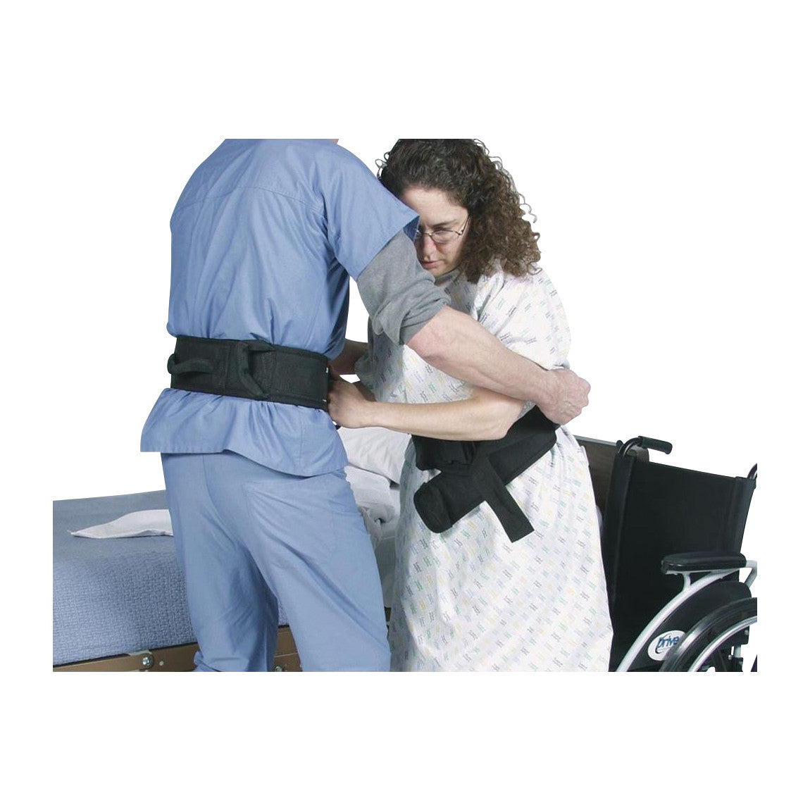 A caregiver assists a patient using a SafetySure Transfer Belt near a wheelchair, likely aiding in movement or transfer.