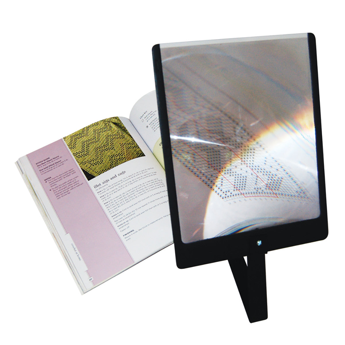 A Prop-It Portable Hands-Free Page Magnifier stands in front of an open book, enlarging text and images for easy reading.