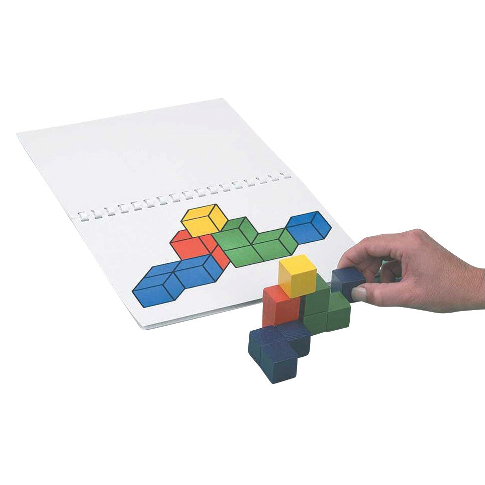 A hand arranges colored cubes to match a 3D pattern on paper. This is the Cognitive Performance Test, Revised (CPT) set.