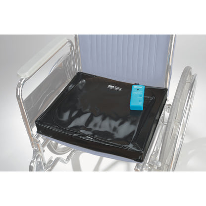 A wheelchair with a SkiL-Care Gel-Foam Pad Alarm on the seat, featuring a black cushion and a blue alarm device.