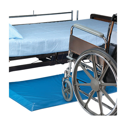 A wheelchair is positioned beside a bed with blue sheets over a SkiL-Care Bi-Fold Roll-On Bedside Mat, providing safety and comfort.