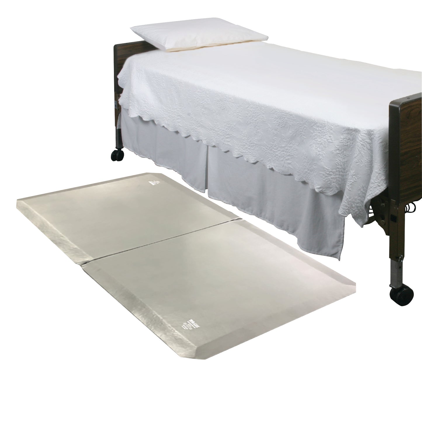 A bed with a white cover and pillow is shown with a SkiL-Care SafeSide Bi-Fold Fall Mat on the floor beside it.