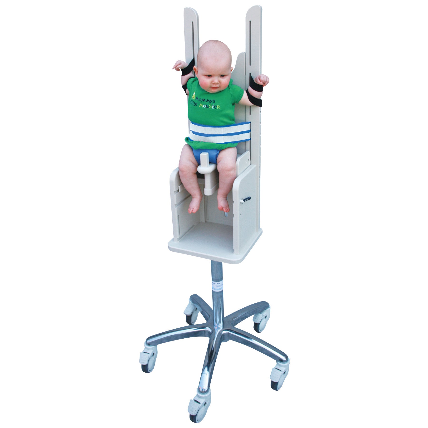 A baby is secured in a Pedia Poser, a medical imaging chair with straps and a metal base with wheels, designed for stability.