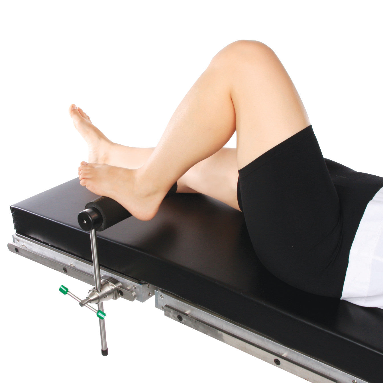 A person uses the AliMed Radiolucent Total Knee Replacement (TKR) Support on a black medical table, with one leg bent.