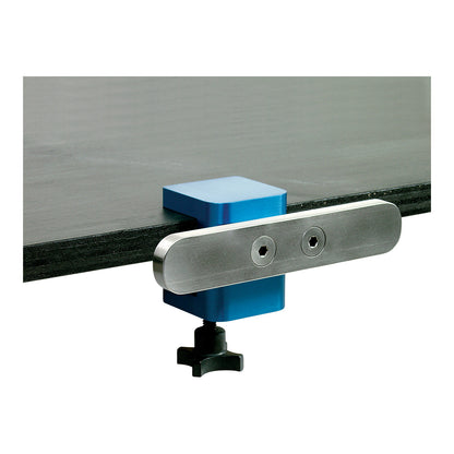 The AliMed FREEDOM O.R. Side Rail Section is attached to the edge of a black table, secured with a blue clamp and a black knob.