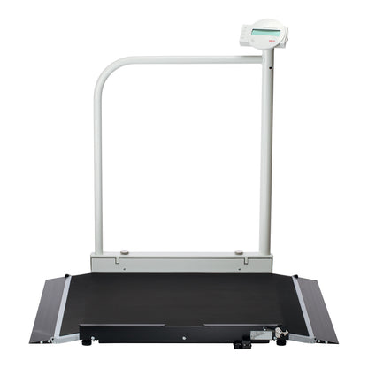 The seca 676 Electronic Wheelchair Scale with Handrail features a flat platform and an integrated digital display on a pole.