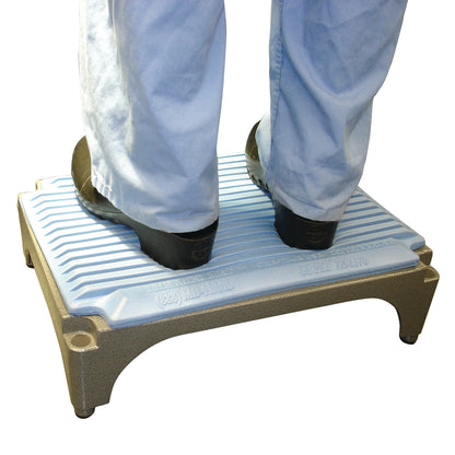 Person standing on a Flagship Surgical Mini Mat, which is a small, textured platform with a blue surface and a beige base.