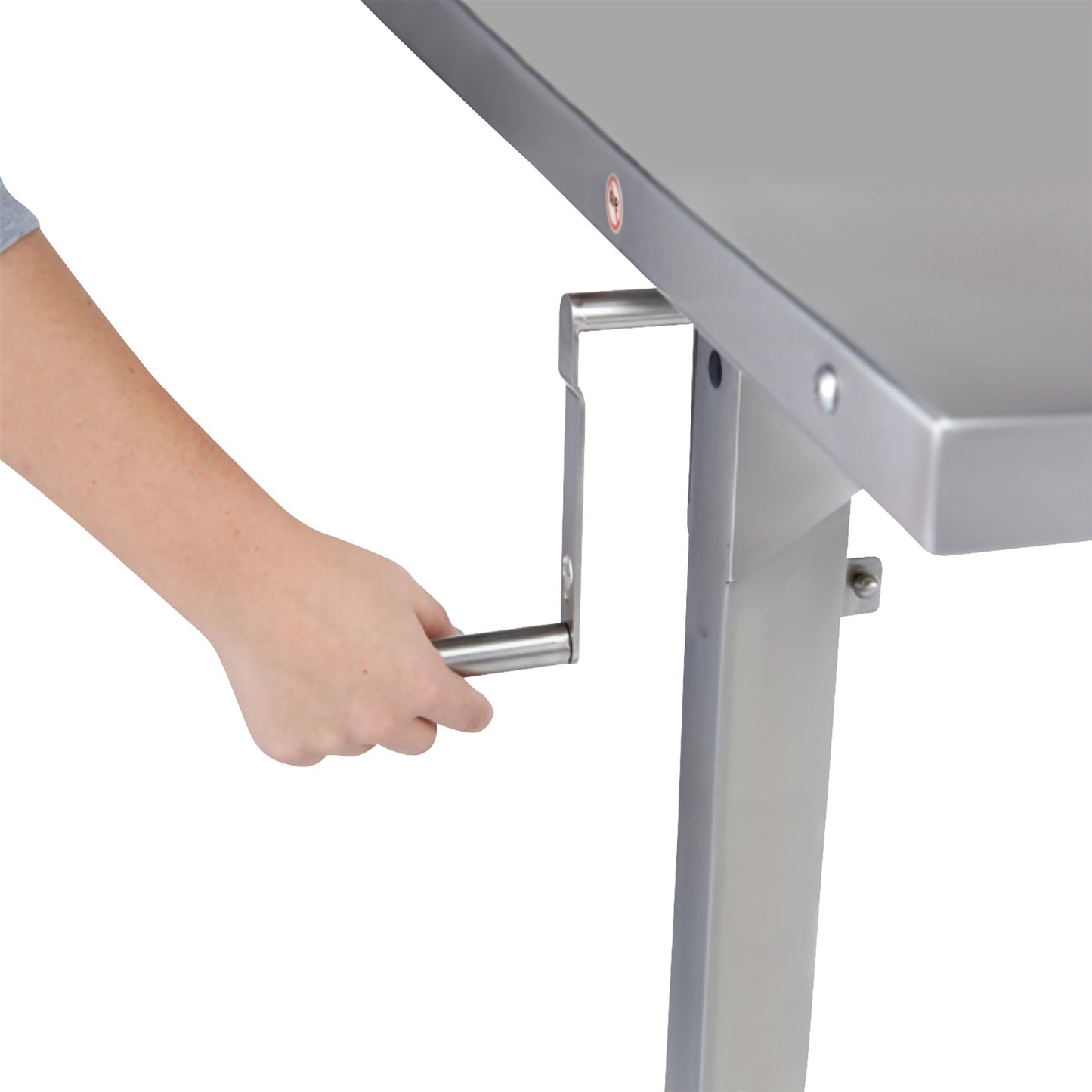 A hand operates the crank of a Blickman Georgetown Manual Adjustable Instrument Table, showcasing its adjustable height feature.