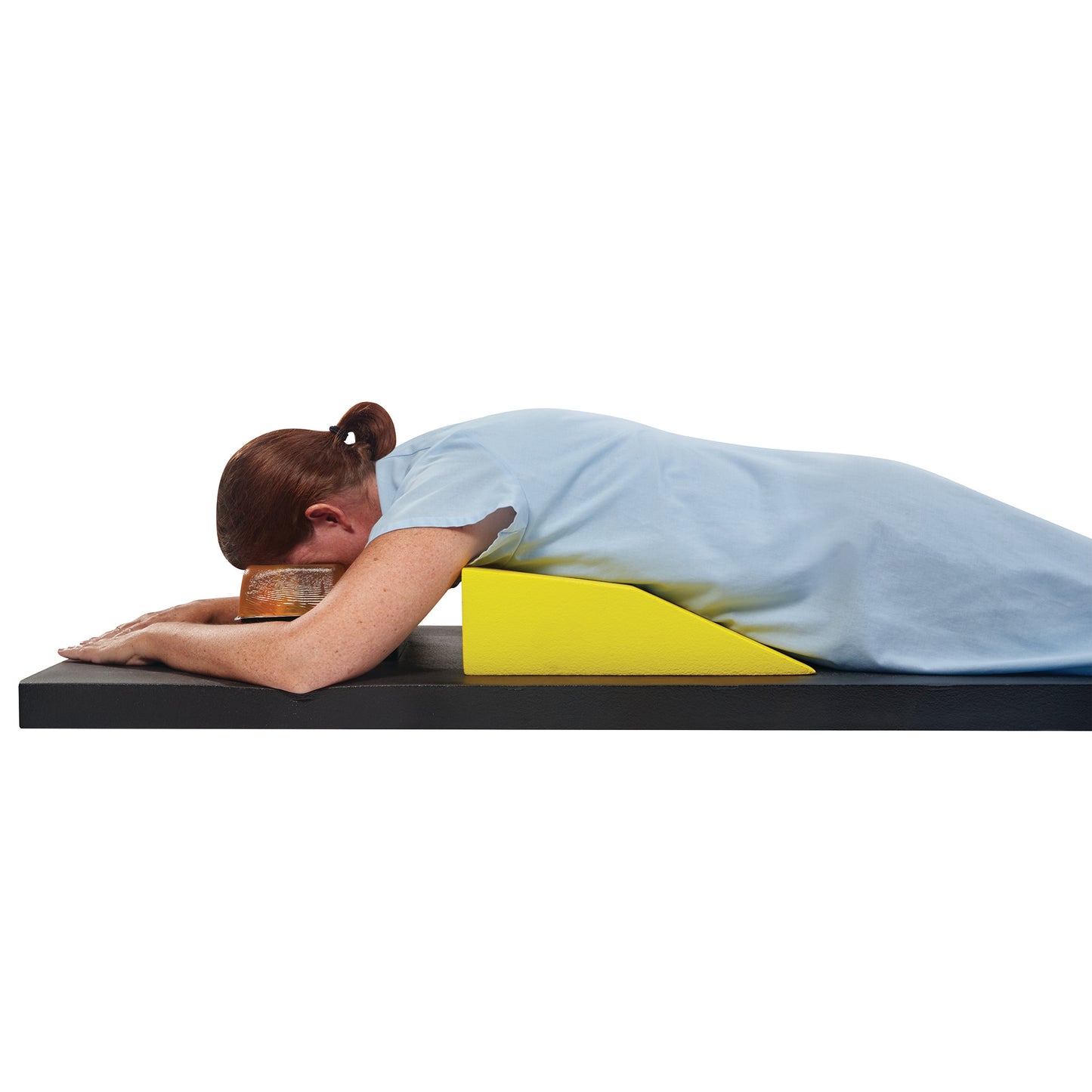 A person lies facedown on an AliMed Protecta-Coat Female Prone Positioner, featuring a yellow wedge support and a head cushion.