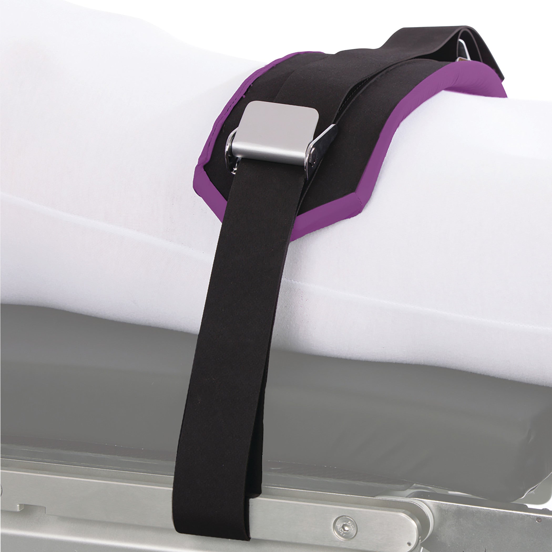 A KYRA Patient Safety Strap secures an individual's leg on a hospital bed with a black strap and silver buckle.