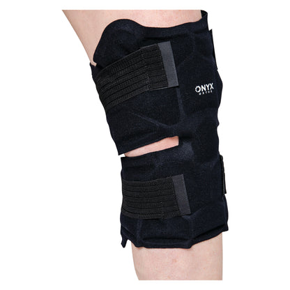 A person wears a Xena Therapies Onyx Cool Knee brace with black straps on their leg, providing support and compression.