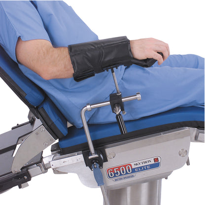 A person in scrubs is seated on a Skytron 6500 Elite table, using a Replacement Pad for Allen Lateral and Prone Arm Support.