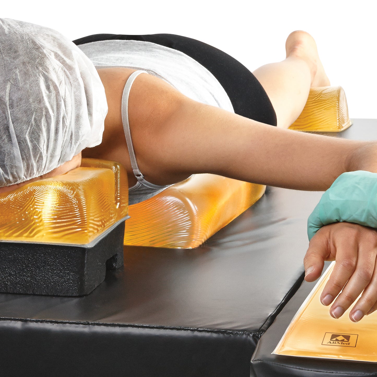 A person lies face down using the AliMed AliGel Chest Roll for support, with additional gel pads beneath their shoulders and arms.