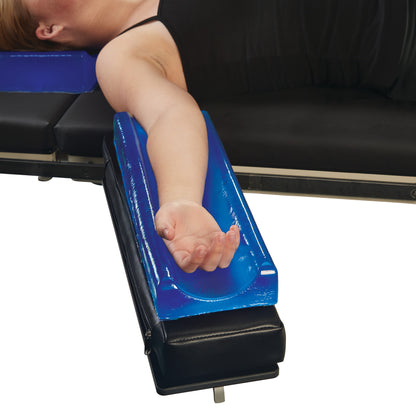 A person's arm rests on the AliMed AliBlue Gel Contoured Armboard Pad, providing comfort and support on a medical table.