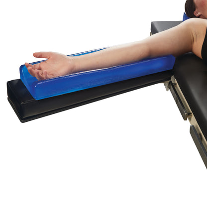 A person's arm rests on an AliMed AliBlue Gel Contoured Armboard Pad, positioned on a black support surface.