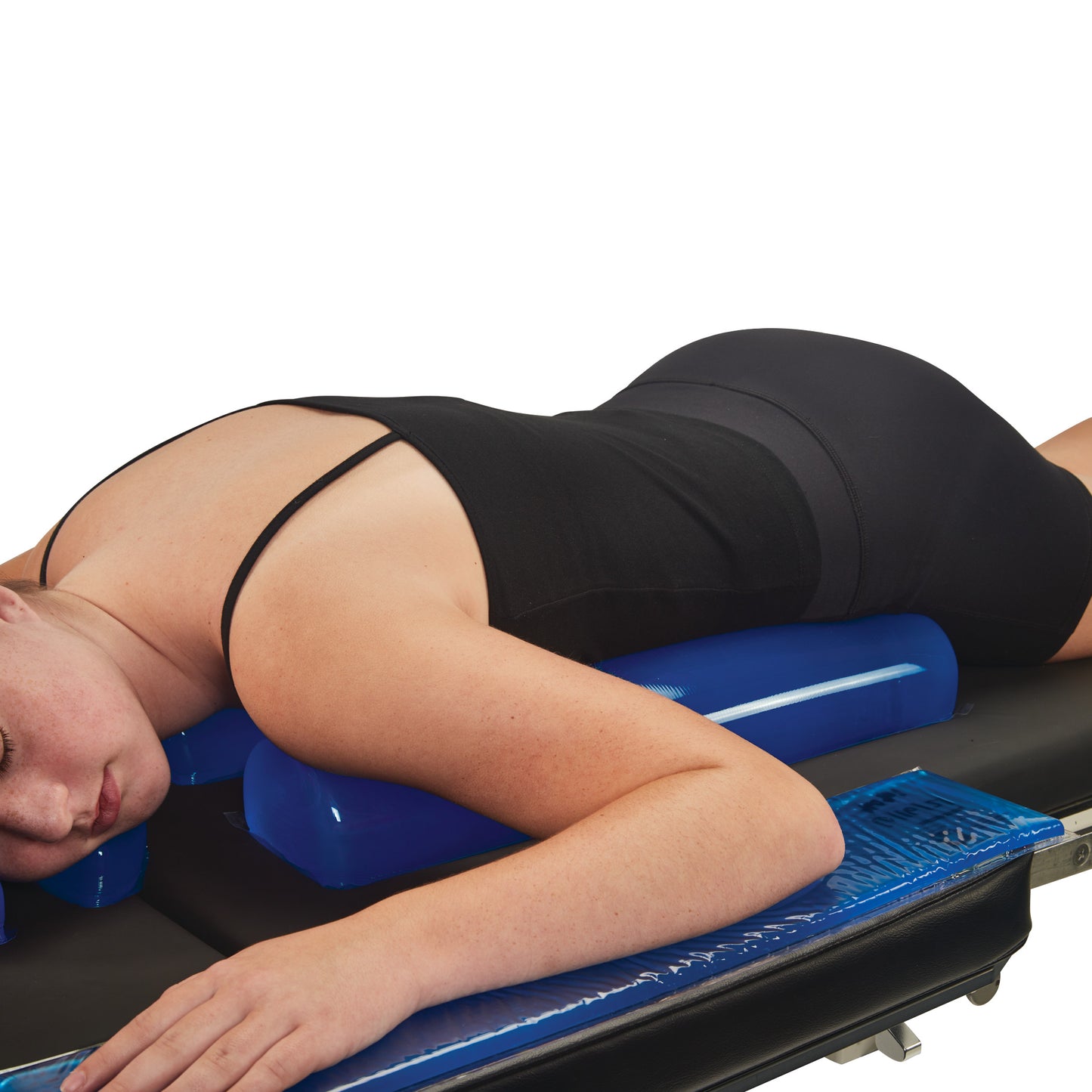 A person lies face down on an AliMed AliBlue Gel Chest Roll, which is positioned on a black surface for support and comfort.