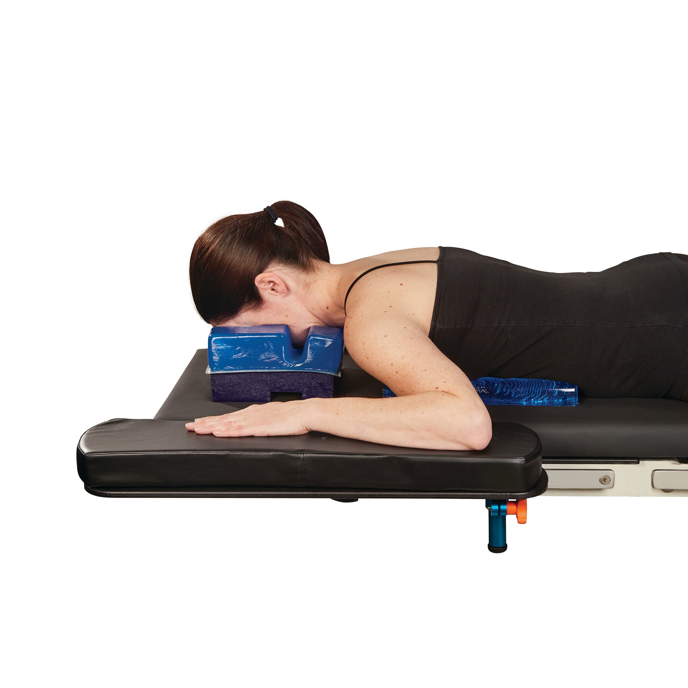A person lies face down using the AliMed AliBlue Gel Prone Head Pad on a massage table. The pad provides head support.