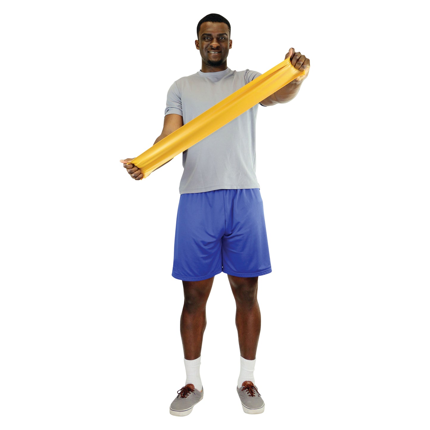 A person in a gray shirt and blue shorts stretches a yellow CanDo Latex Exercise Band with both hands, standing on a white background.