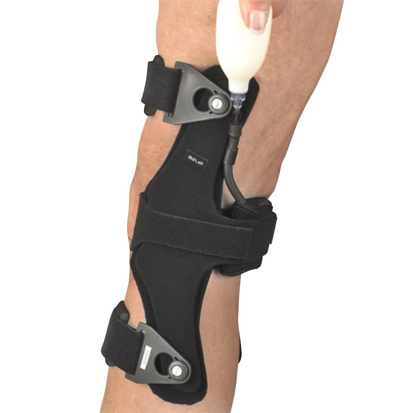 A person adjusts the OrthoPro HyperEx Knee Orthosis on their leg using a white pump. The brace features black straps and hinges.