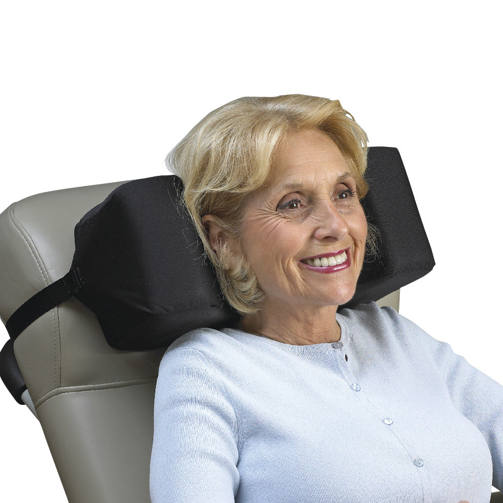 The SkiL-Care Reclining Wheelchair Headrest supports an older woman sitting in a chair, ensuring comfort and head stability.