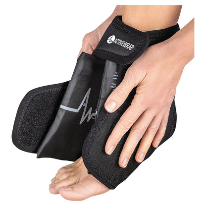 Hands are adjusting an ActiveWrap ankle support around a foot. The wrap is black with a strap.