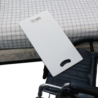 A SafetySure Transfer Board is placed between a plaid-covered bed and a wheelchair, providing a transfer aid for mobility assistance.