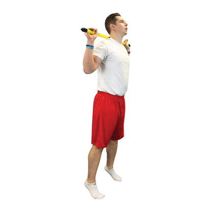 A person in a white shirt and red shorts lifts a yellow CanDo WaTE Bar on their shoulders, standing on one foot in socks.