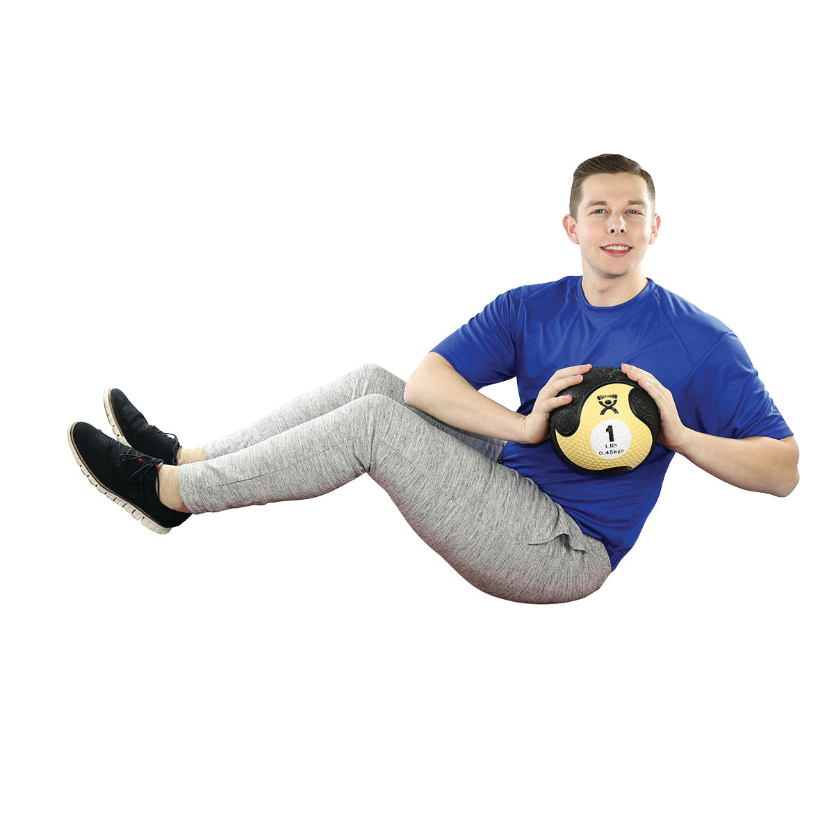A person exercises with a CanDo Rubber Medicine Ball, holding it while sitting, wearing a blue shirt and gray pants.
