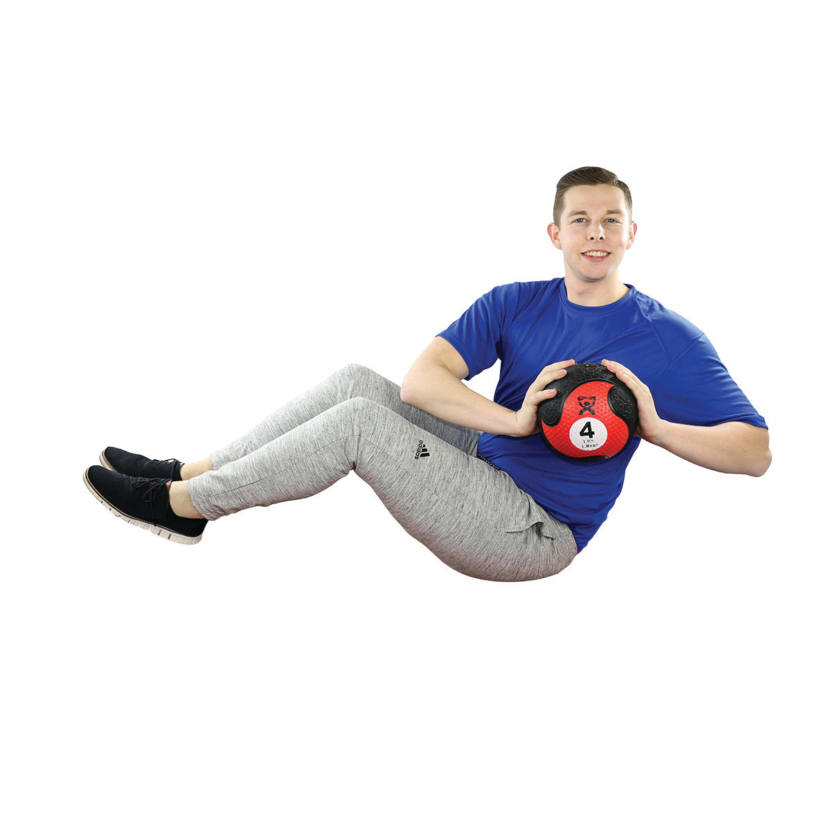 A person in exercise attire performs a twist holding a CanDo Rubber Medicine Ball weighing 4 pounds, balancing on their tailbone.