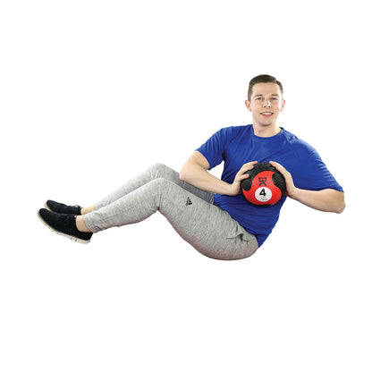 A person in exercise attire performs a twist holding a CanDo Rubber Medicine Ball weighing 4 pounds, balancing on their tailbone.