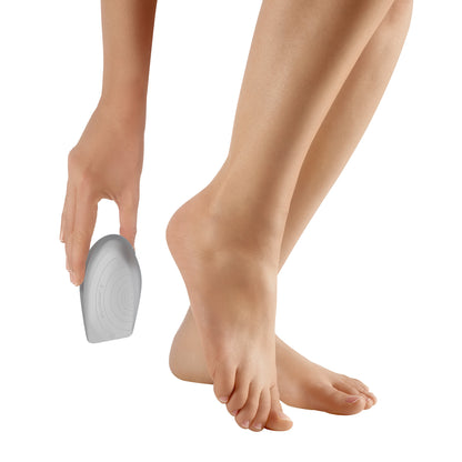 A person holds the Bauerfeind ViscoHeel K Heel Cushion near their bare feet. The cushion is gray and ergonomically shaped.