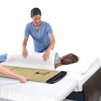A healthcare worker uses an AliMed Soft Gold Rollboard to assist in transferring a patient lying on a bed.