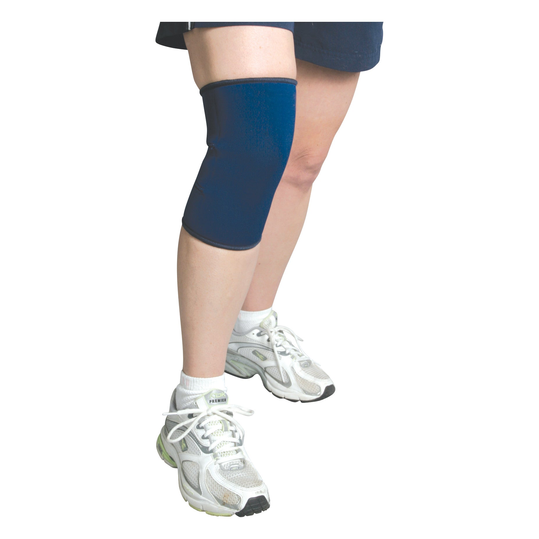 A person wearing the AliMed Knee Support with Closed Patella in blue, along with shorts and white sneakers.