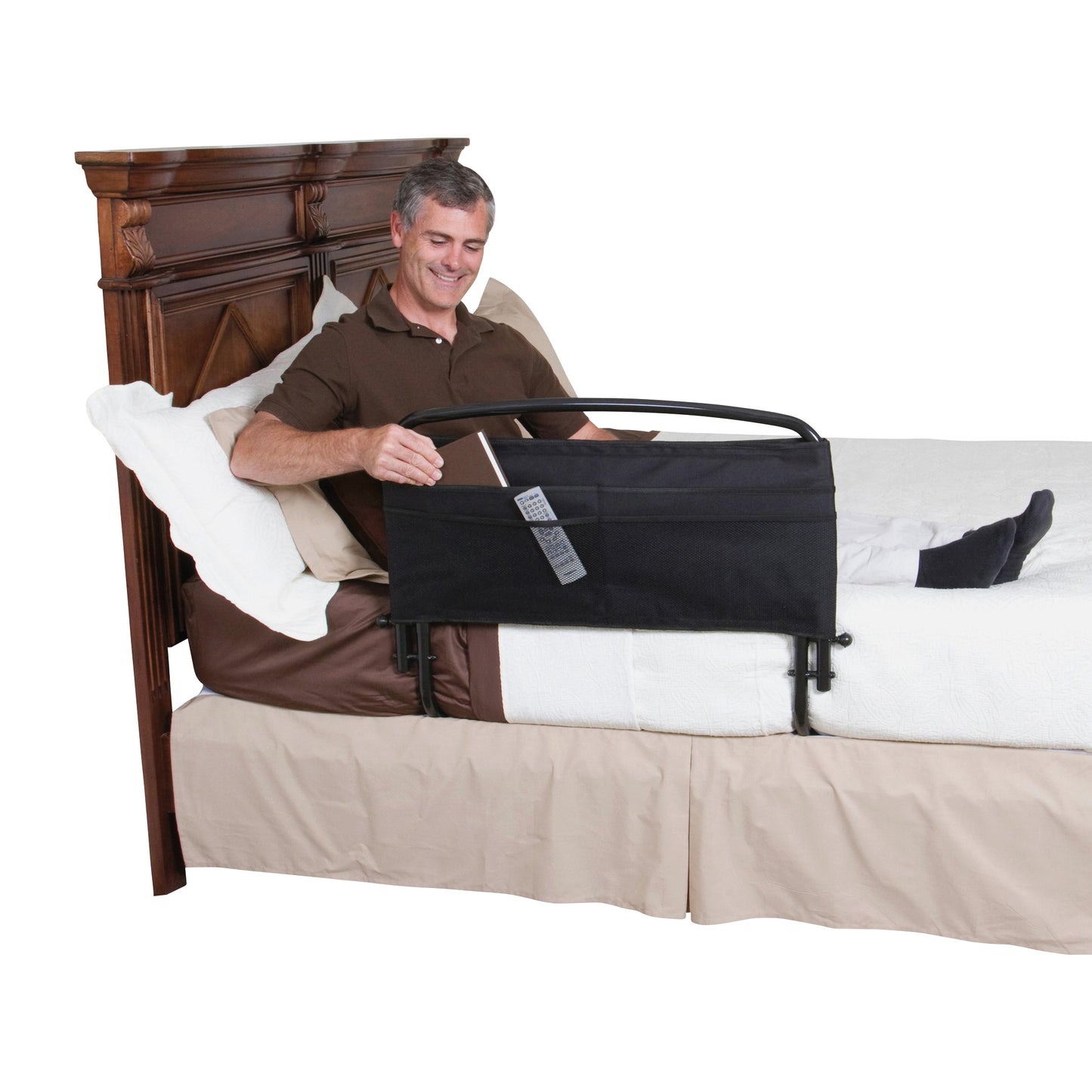 A man sitting on a bed uses a Stander 30" Safety Bed Rail with a pouch holding a remote and a magazine.