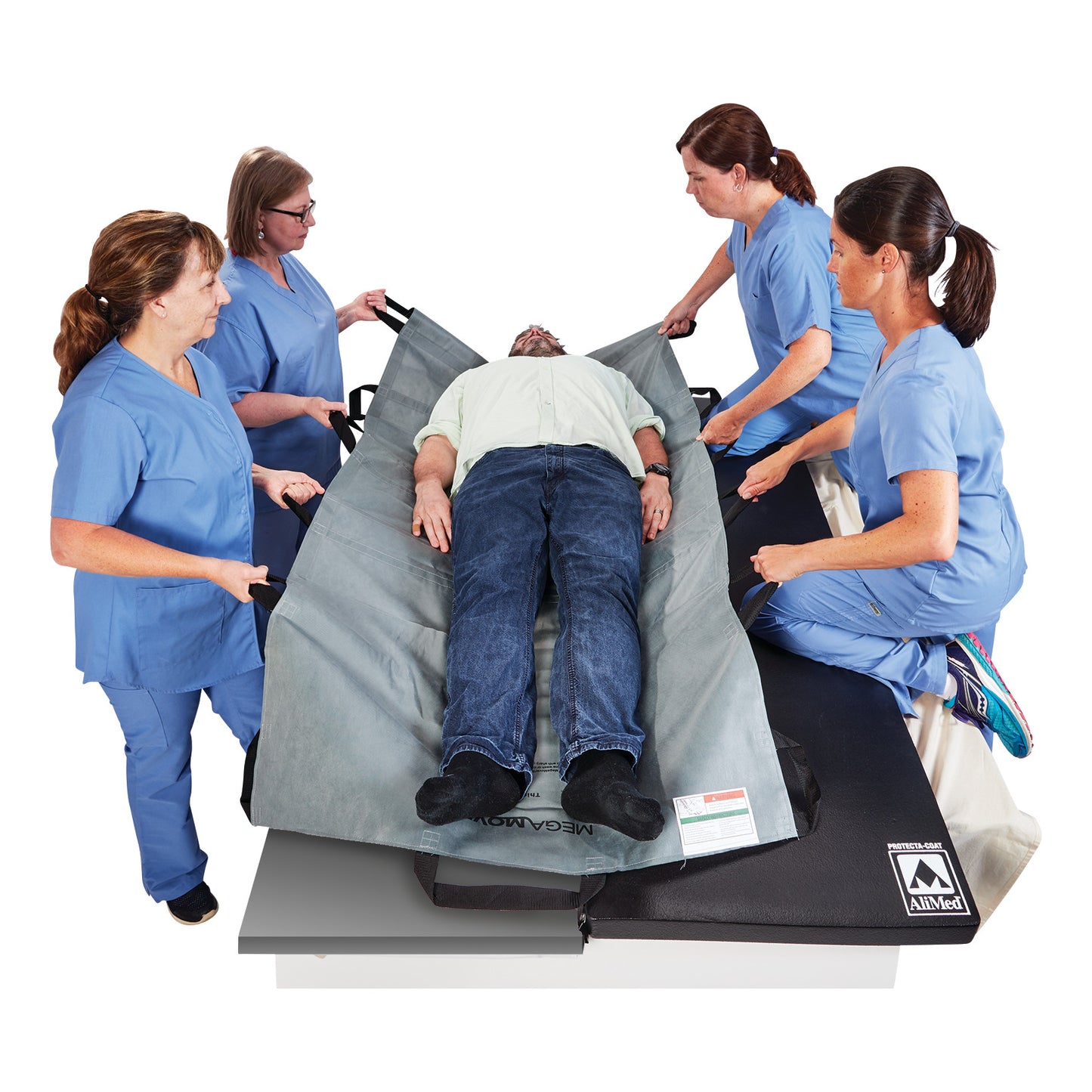 Four medical workers in blue scrubs transfer a patient using a Graham Medical MegaMover Plus Transport Unit.