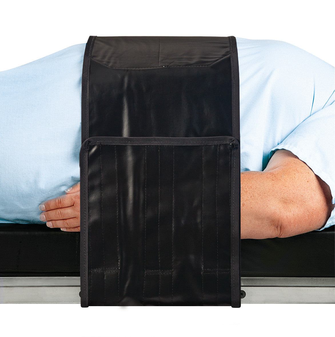 A person is lying on a surface with the AliMed Nonmetallic Operating Room Table Strap with Compression Pad across their back.
