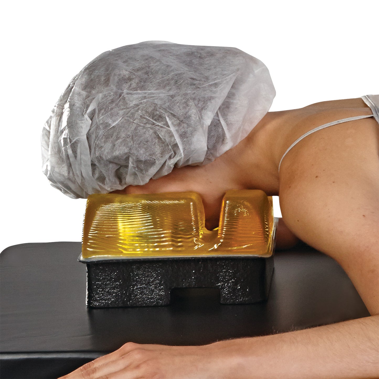 A person is resting face down on an AliMed AliGel Prone Head Pad, with a disposable cap on a massage table.