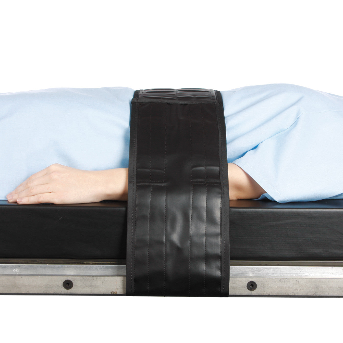 A patient on a table is secured with an AliMed Nonmetallic Operating Room Table Strap with Compression Pad across their torso.