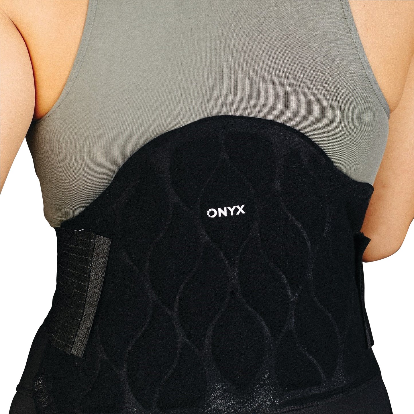 A person wearing the Xena Therapies Onyx Cool Back/Hip, a black back support with a wave pattern and "ONYX" logo, over a grey top.