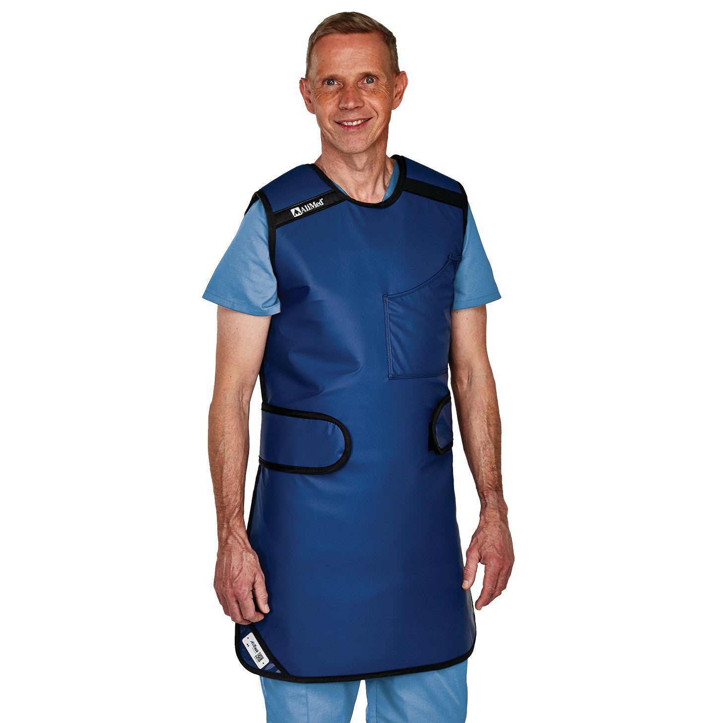 A person wearing an AliMed Grab n Go Flex Weight Reliever Apron, Male, over light blue scrubs, standing and smiling.