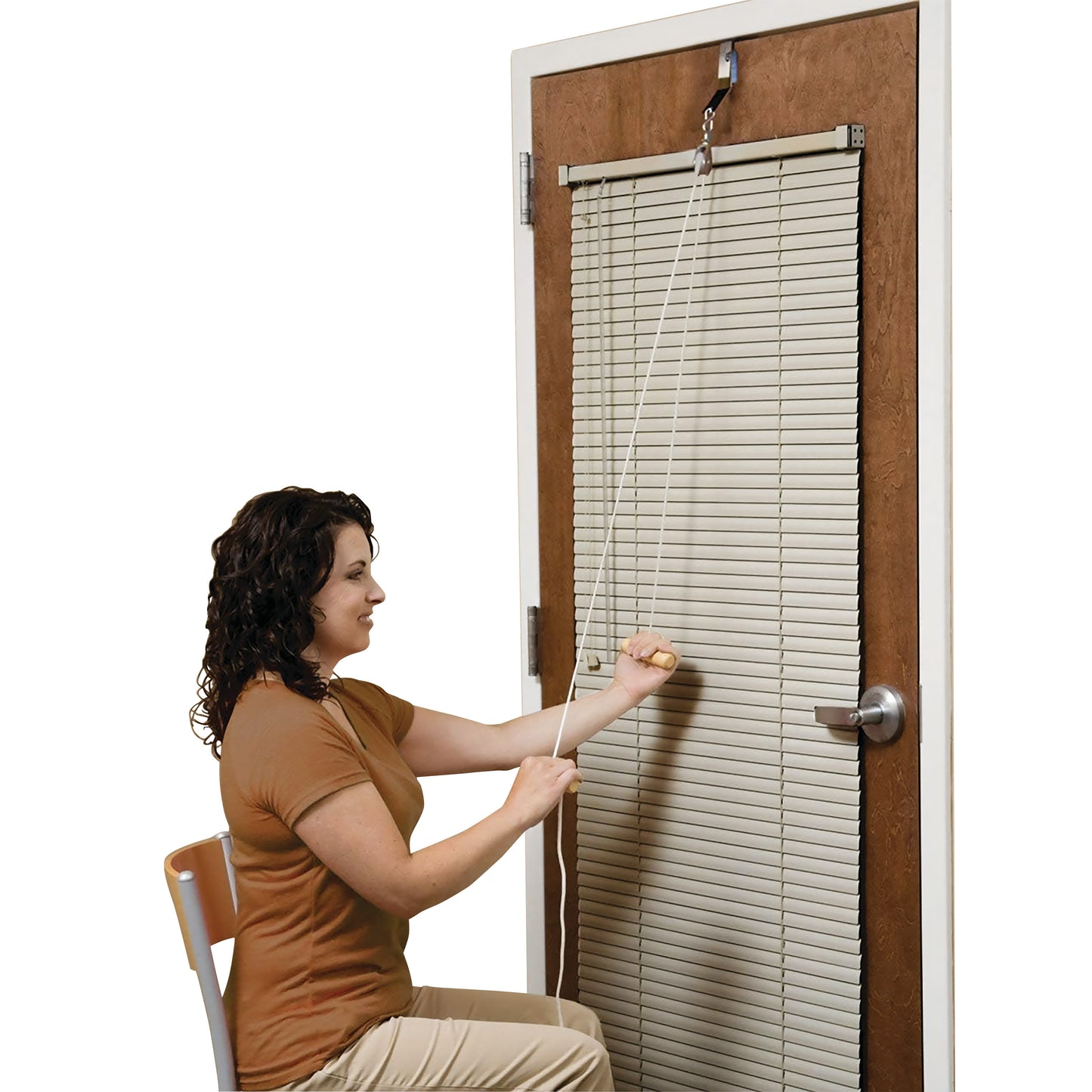 A woman uses the RangeMaster EconoRanger Shoulder Pulley attached to a door, performing an arm exercise while seated.