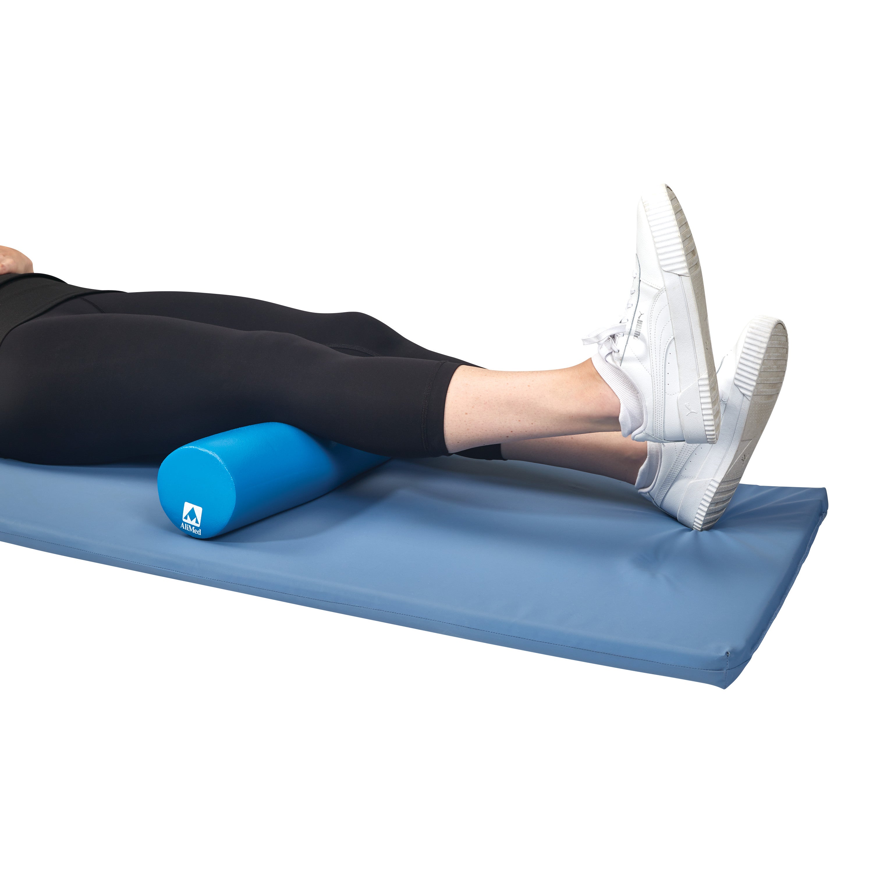 Person using the AliMed Antimicrobial-Treated Therapy Positioning Wedge under their legs on a blue mat, wearing white sneakers.