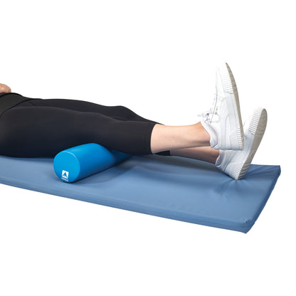 Person using the AliMed Antimicrobial-Treated Therapy Positioning Wedge under their legs on a blue mat, wearing white sneakers.