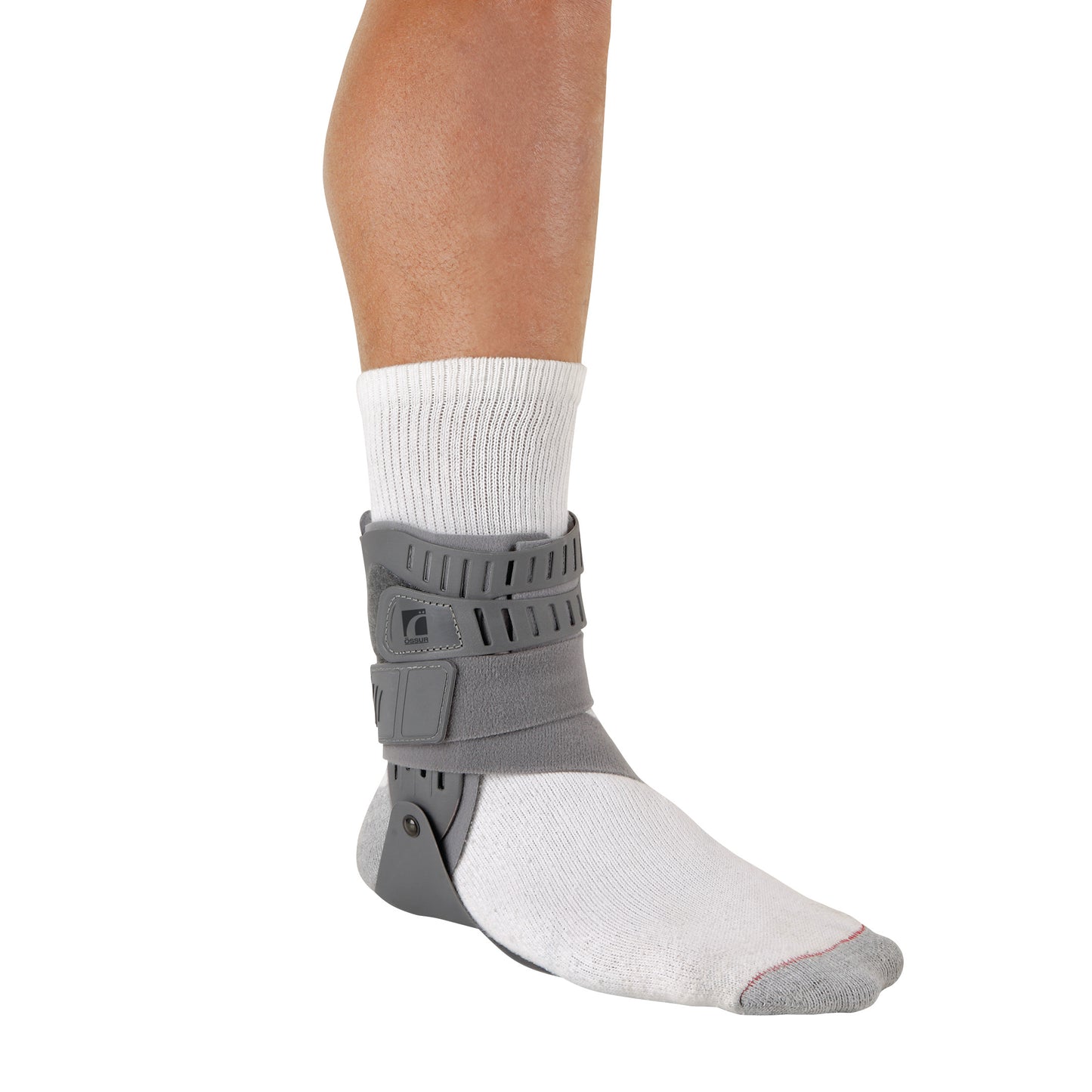 A leg wearing a white sock fitted with an Ossur Rebound Ankle Brace in gray, providing support around the ankle and foot.