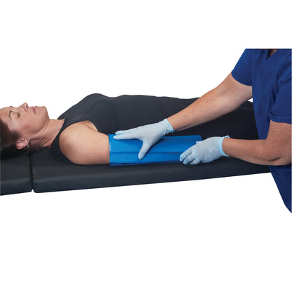 A person lies on a mat while another person positions an AliMed AliBlue Gel Ulnar Forearm Protector under their arm.
