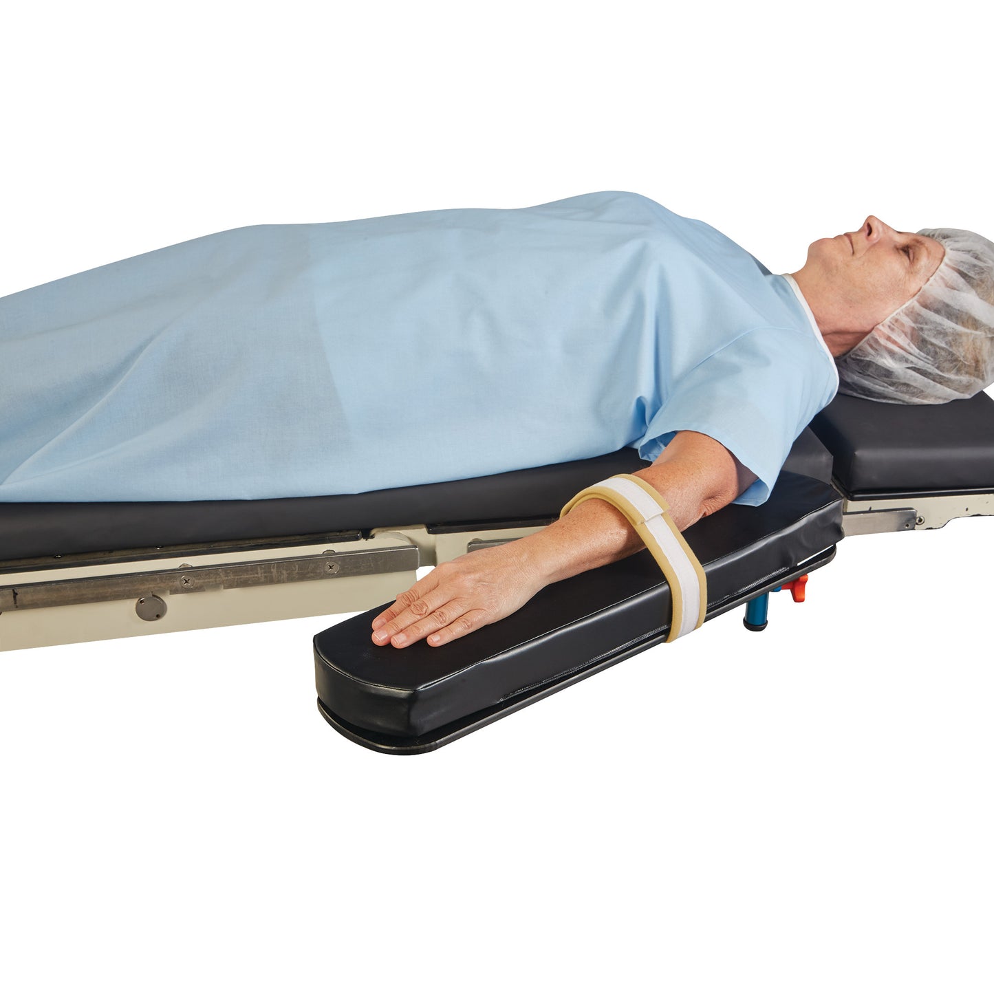 A patient lies on a bed with their arm secured by an AliMed AliStrap Soft Precut Patient Safety Strap, wearing a blue gown and hair cover.