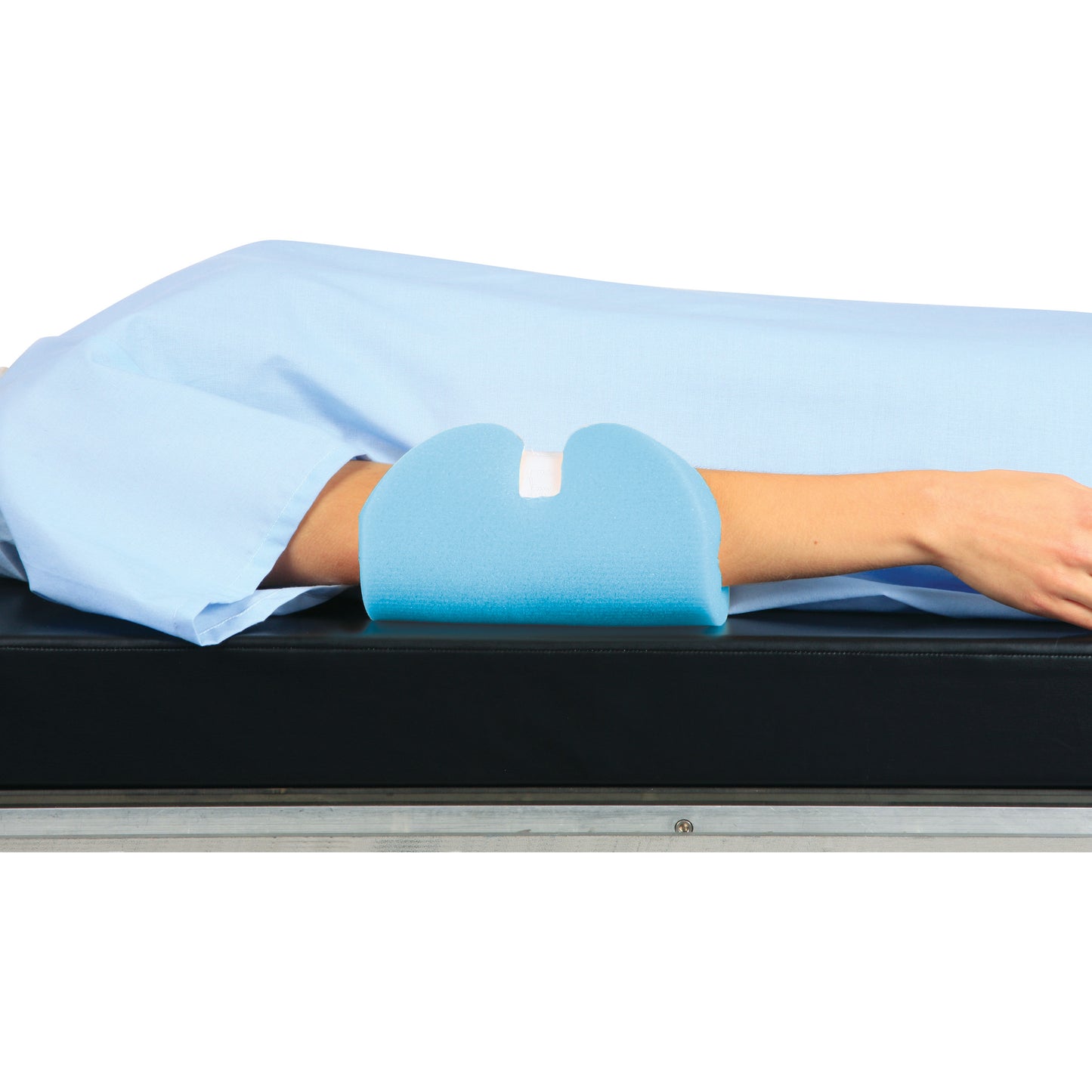 A person's arm is resting on an AliMed Single-Use Ulnar Nerve Protector, a blue foam cushion, on a black surface.