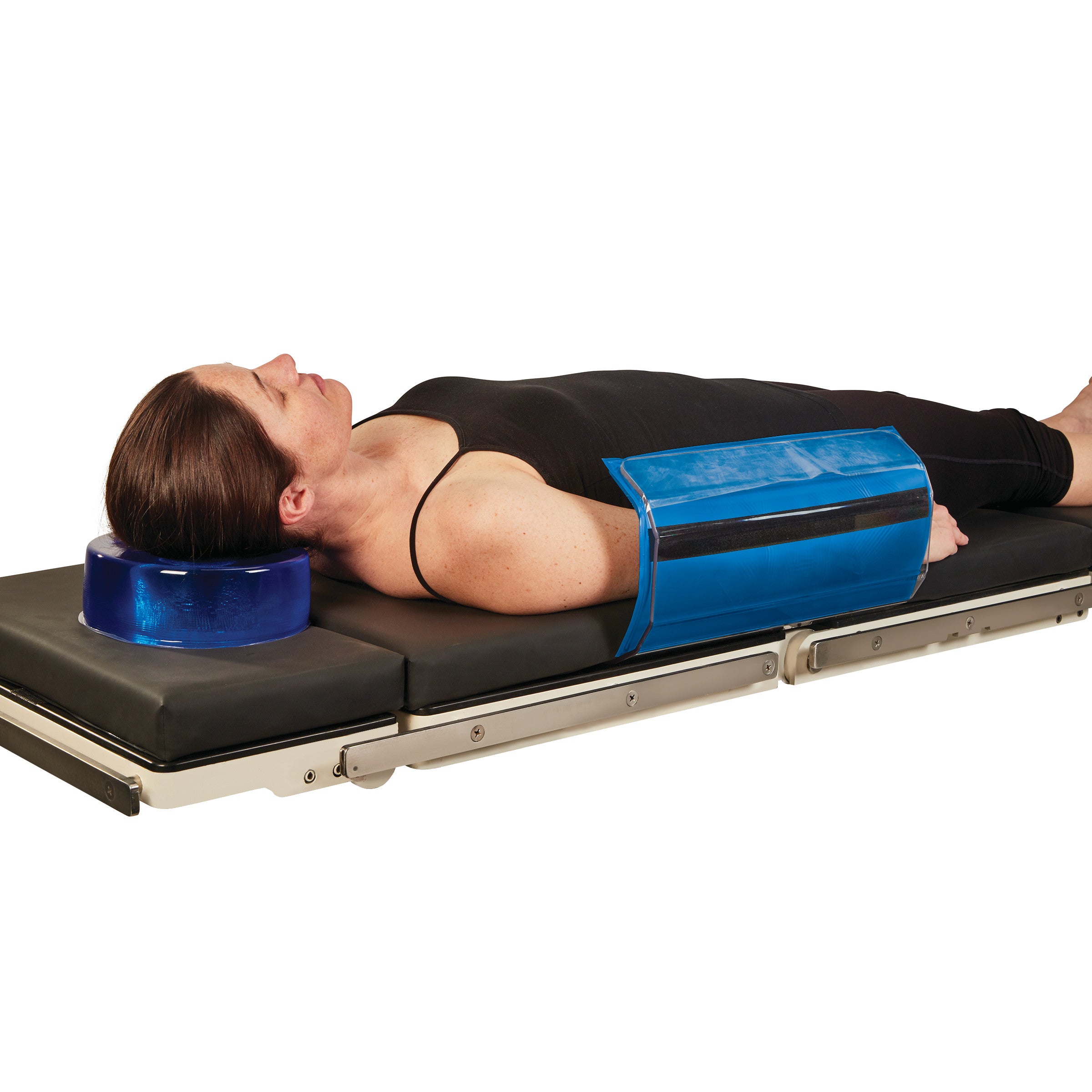 A person lies on a padded table using the AliMed AliBlue Gel Toboggan Pad on their side and a gel pillow for neck support.