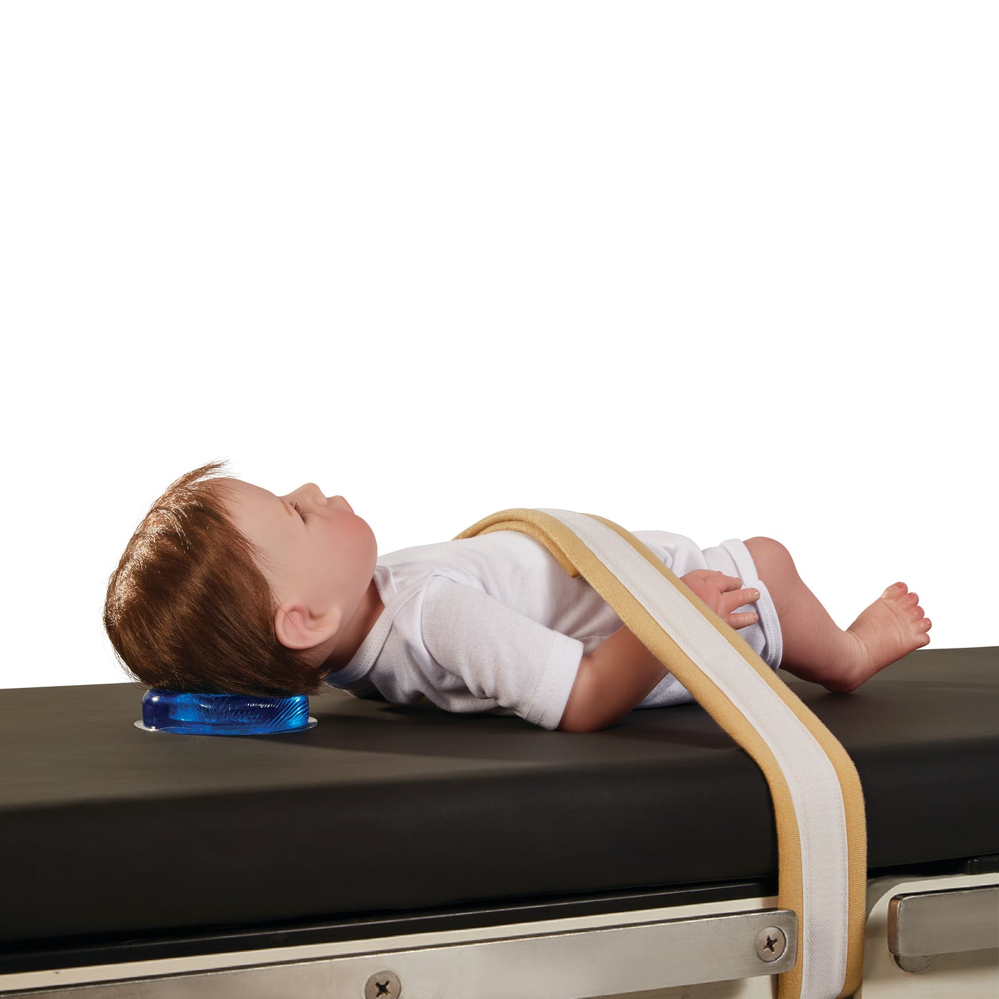 A doll is shown on a medical table with the AliMed AliBlue Gel Head Donut supporting its head. A strap secures the doll's abdomen.