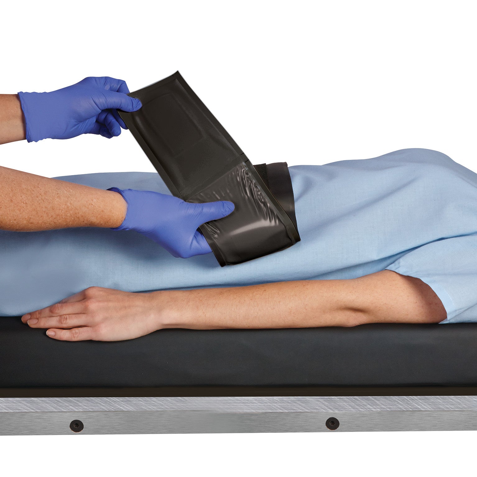 A person fastens an AliMed AliGel Surgical Table Strap over a patient's arm. The strap is black with a yellow gel section.